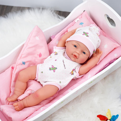 Baby doll inside a pink and white box with a stuffed animal nearby.