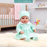 A doll wears a mint green knit outfit with a collar and hat, sitting on a white surface.
