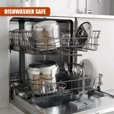 Silver pots, plates, and cutlery resting on stacked, stainless steel dishwasher racks.