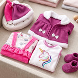 Doll clothing set featuring a purple coat, unicorn top, pink patterned shirt, and matching purple booties.