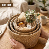 Hand holding a nested trio of woven wicker planters filled with flowers and small gifts.