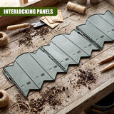 A row of curved, interlinking gray garden edging panels rests on a dusty wooden surface.