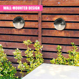 Two black, dome-shaped solar lights are mounted on a wooden fence next to green shrubs.