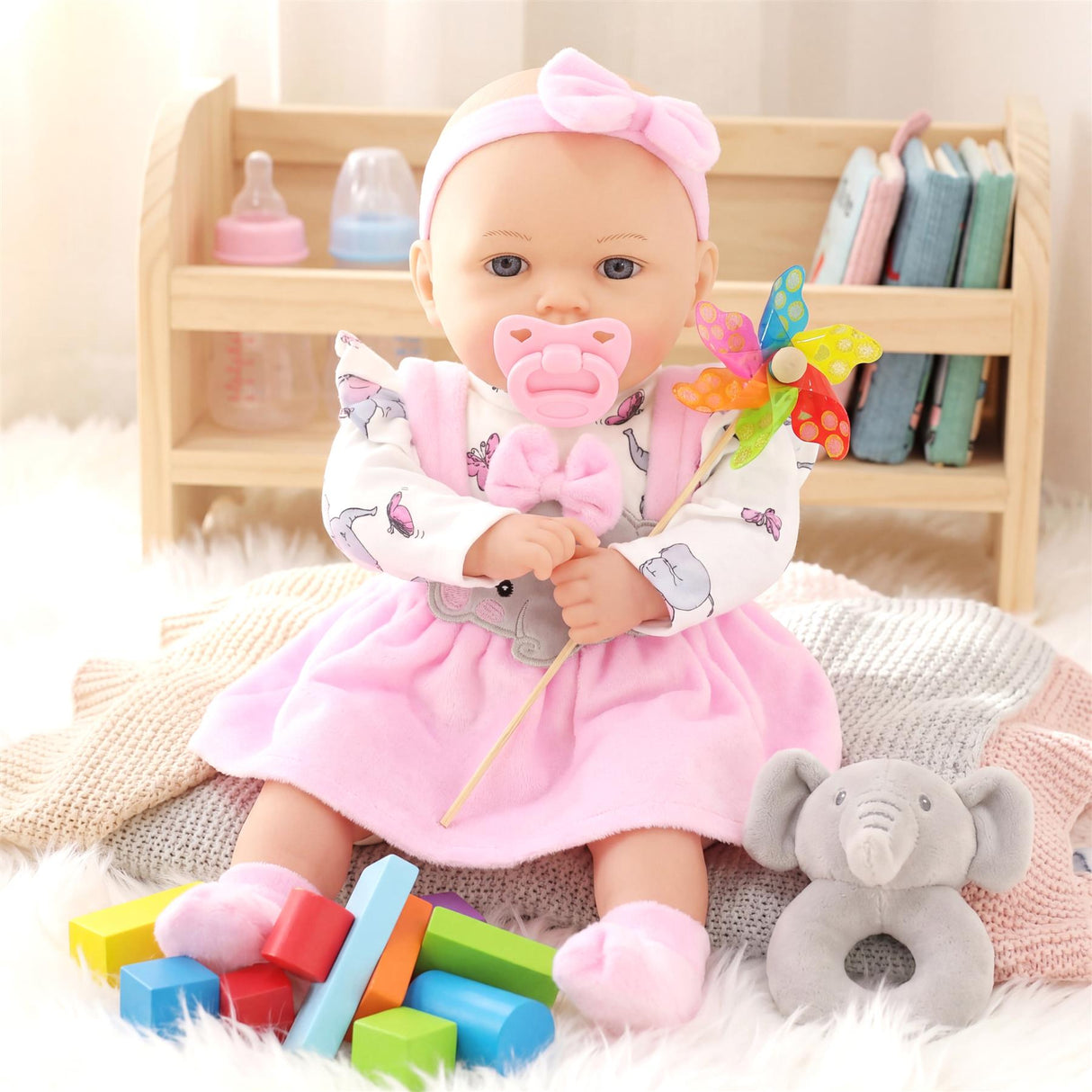 Doll seated among colored blocks, a stuffed elephant, and a wooden changing table setup.