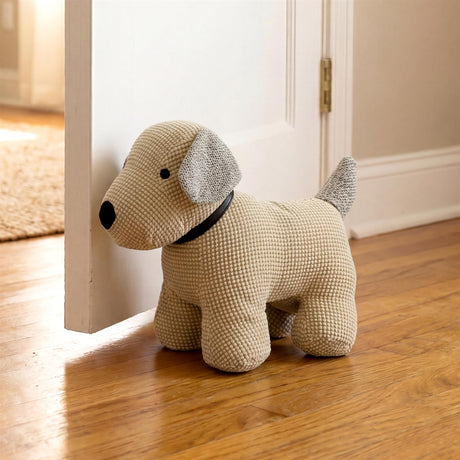 Knitted stuffed dog novelty door stopper rests near white painted interior doorway.