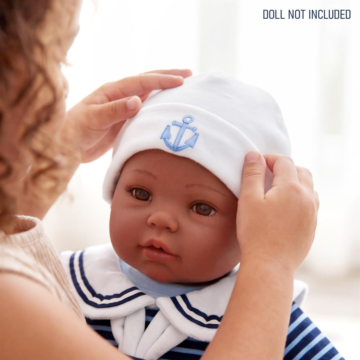 A doll is shown wearing a sailor outfit and a white hat with a blue anchor embroidered on the band.