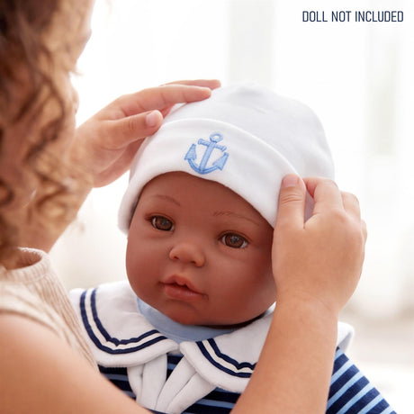 A doll is shown wearing a sailor outfit and a white hat with a blue anchor embroidered on the band.