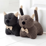 Grouping of three knitted stuffed animal figures in gray and brown, sitting on a white surface.