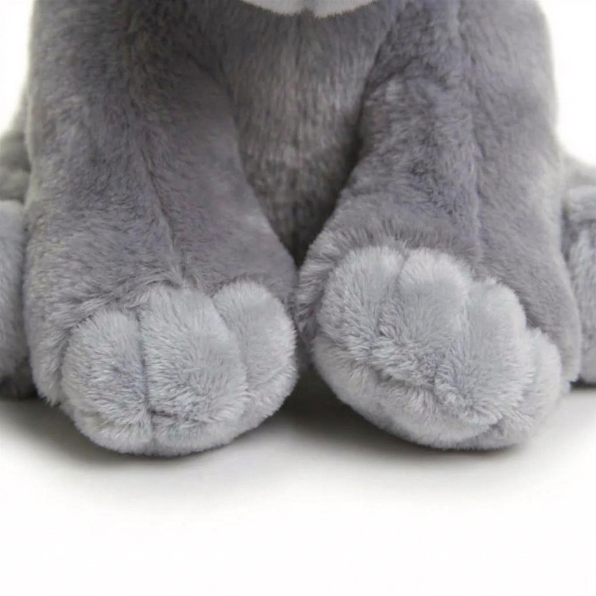 Detailed view of the soft, gray plush feet of an elephant stuffed toy.