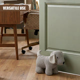 A gray stuffed dog novelty door stopper resting against a pale green doorway frame.