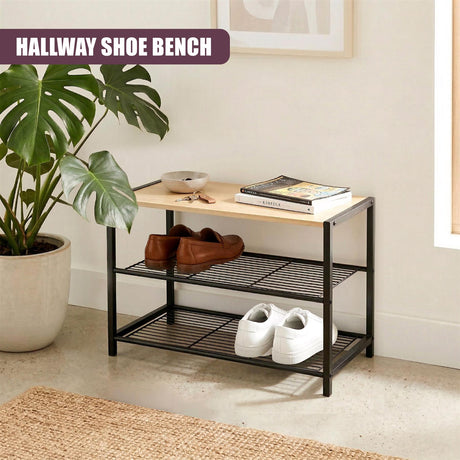 A black, two-tiered shoe bench holding shoes, books, and a bowl on the top surface.