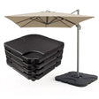 Beige patio umbrella on a stand next to a stack of four dark square outdoor cushions.