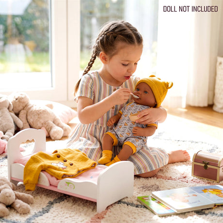Small girl and doll near a changing table, yellow outfit laid out for play.