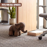 Tartan elephant door stopper rests on a carpet near stacked paper and desk accessory.