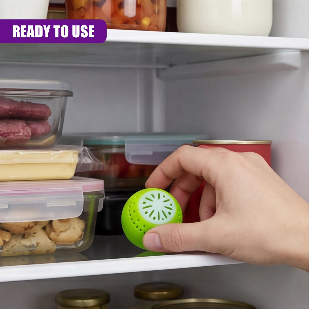 Hand holding a bright green, perforated deodorizer ball near a white refrigerator shelf.