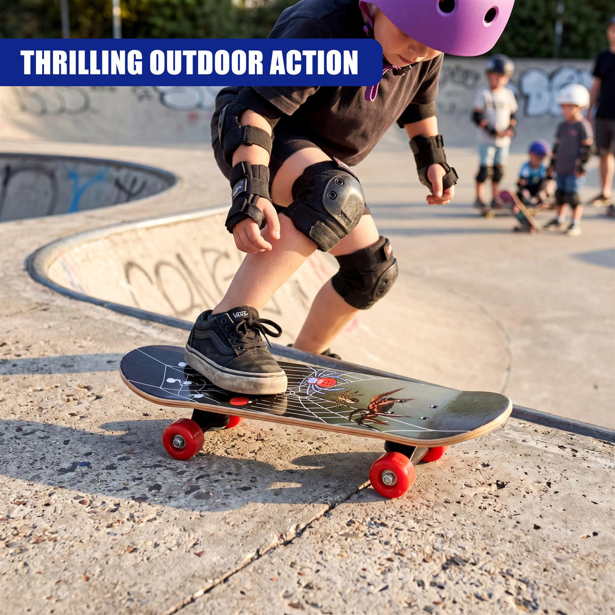 A dark skateboard with graphic decals rests on concrete, featuring four visible red wheels.
