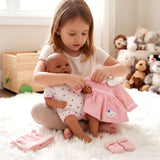 Pink embroidered dress, accessories, and matching outfit displayed on a reborn doll.