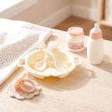 Toy set features a feeding high chair, utensils, baby bottle, jar, and teething rattle on a table.