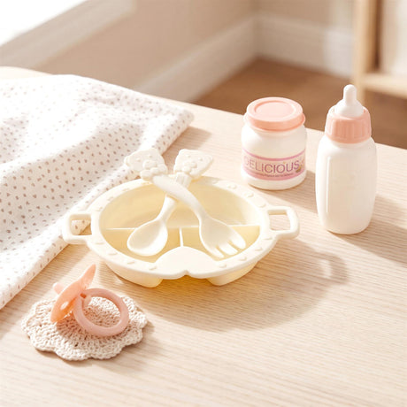 Toy set features a feeding high chair, utensils, baby bottle, jar, and teething rattle on a table.