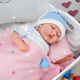 A sleeping doll, wearing stripes and a blue hat, rests in a wooden cradle with a pacifier on the bed.