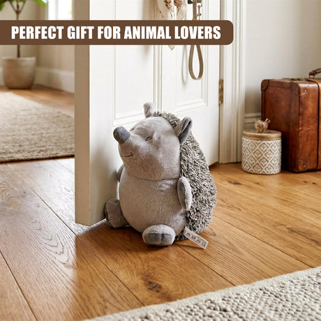 A stuffed hedgehog door stopper, made of textured gray and brown fabric, rests against a white door frame.